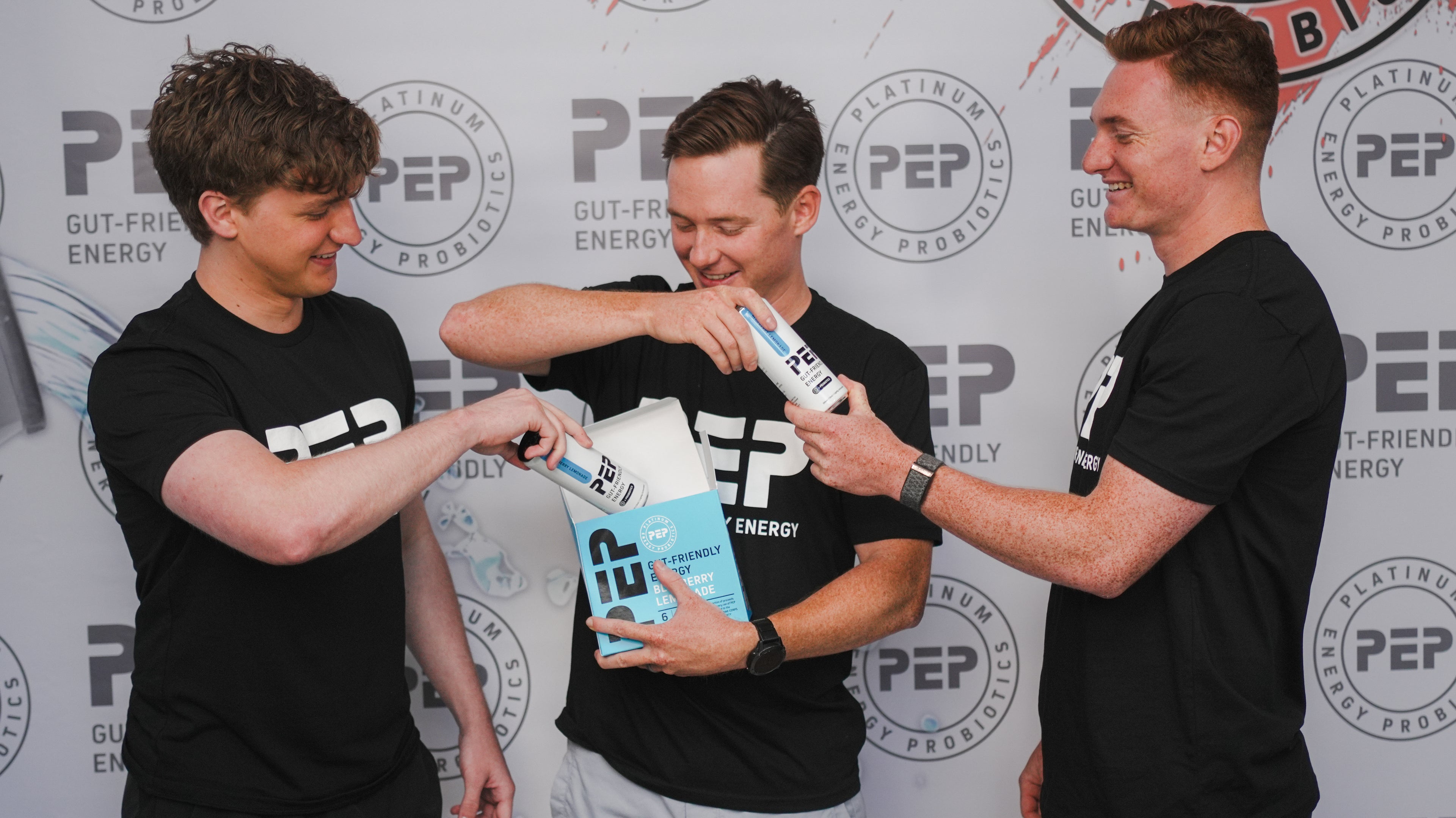 The Beasley brothers in black PEP tee shirts holding PEP Energy products against a PEP-branded background