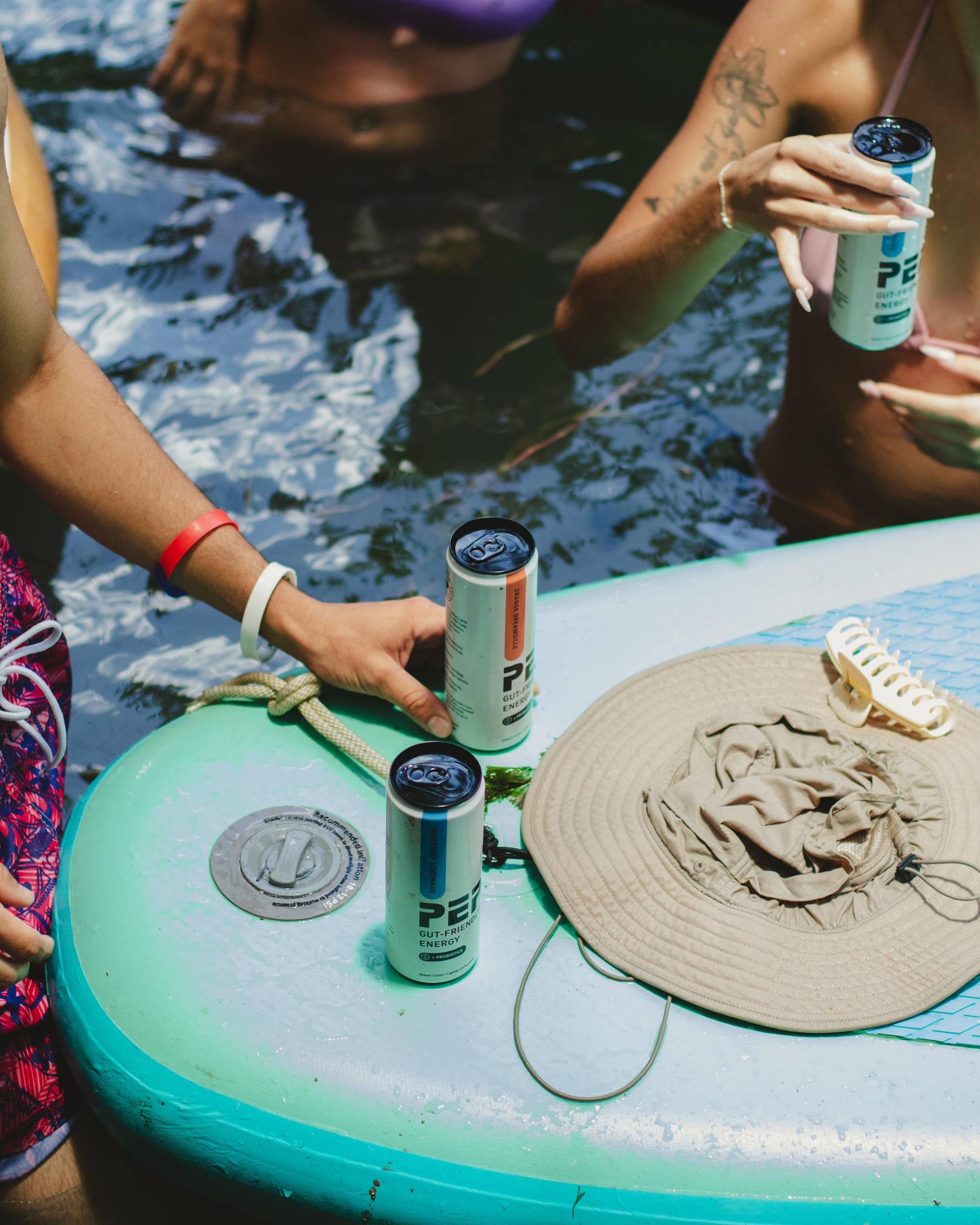People in a pool with PEP Energy cans on a floating paddle board