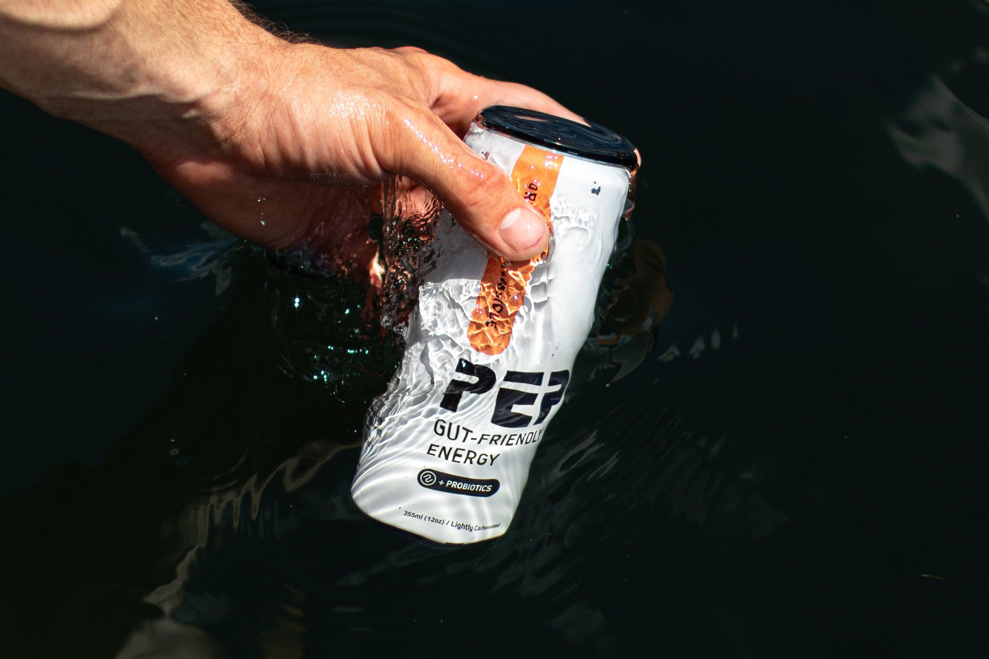Hand holding a white PEP energy drink can with branding against a dark background